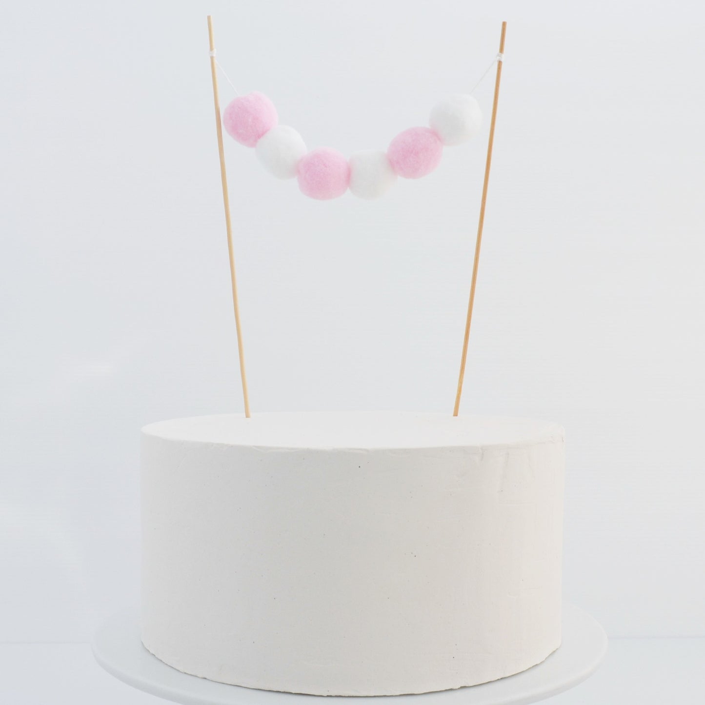 pink and white pom pom cake topper